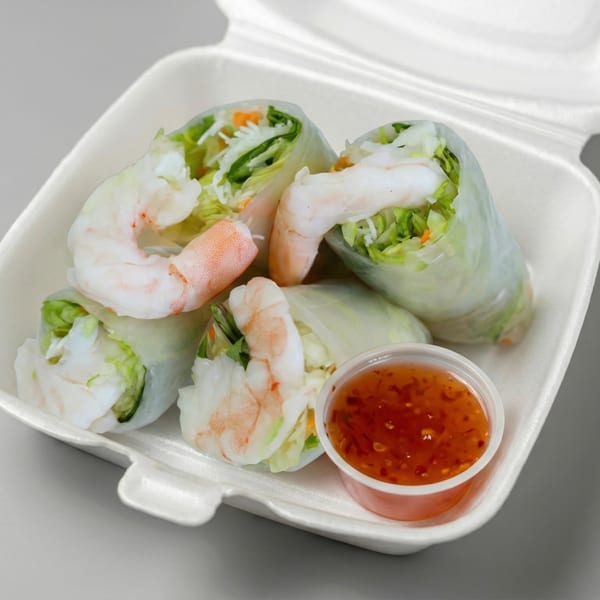 Four fresh shrimp spring rolls with lettuce and carrots, served with a side of sweet chili sauce.